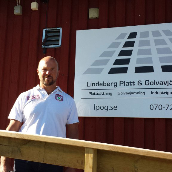 Pelle Lindeberg framför skylten för Lindeberg Platt och Golvavjämning AB i Åkersberga